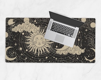 Può includere: Un tappetino da scrivania nero con un design celeste con un sole, una luna, stelle e nuvole in beige e bianco. Un computer portatile argentato è posizionato sul tappetino. Il tappetino ha una forma rettangolare.