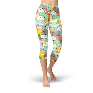 May include: A pair of colorful cat-print leggings with a cropped length. The leggings feature a variety of cats in different colors and patterns.