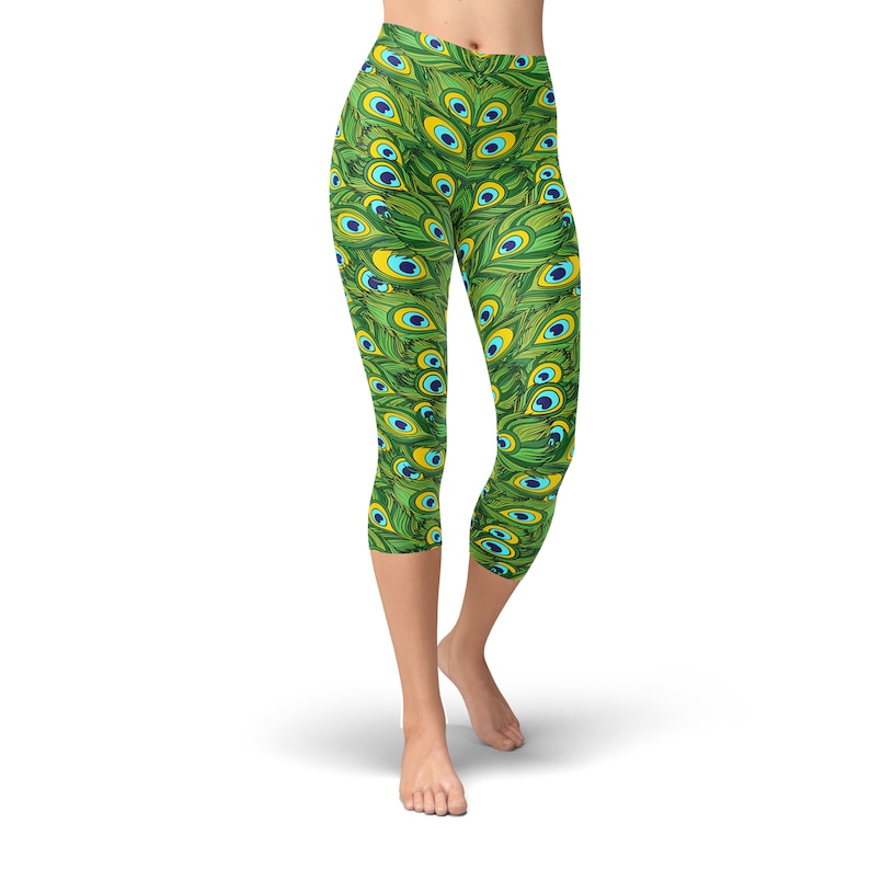 May include: Green capri leggings with a peacock feather pattern. The leggings have a high waist and are made of a stretchy, comfortable fabric.