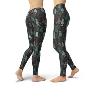 May include: Black leggings with a repeating pattern of stylized cats in teal, gray, and white. The cats are in various poses and designs, creating a playful and whimsical look. The leggings are form-fitting and made of a soft material.