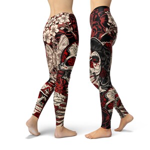 May include: Black leggings with a colorful print featuring a skull, flowers, and butterflies. The skull has red and white details and is surrounded by red roses. The leggings have a black background with white and red accents.