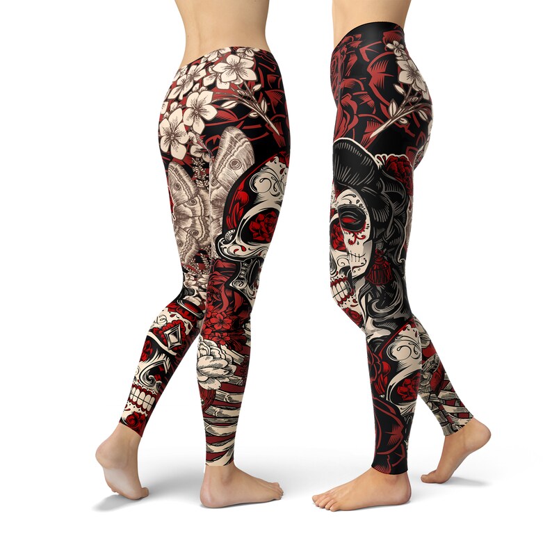 May include: Black leggings with a colorful print featuring a skull, flowers, and butterflies. The skull has red and white details and is surrounded by red roses. The leggings have a black background with white and red accents.