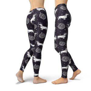May include: Black leggings with a white print of dachshunds wearing astronaut helmets and floating in space. The print also includes white circles with a textured pattern.