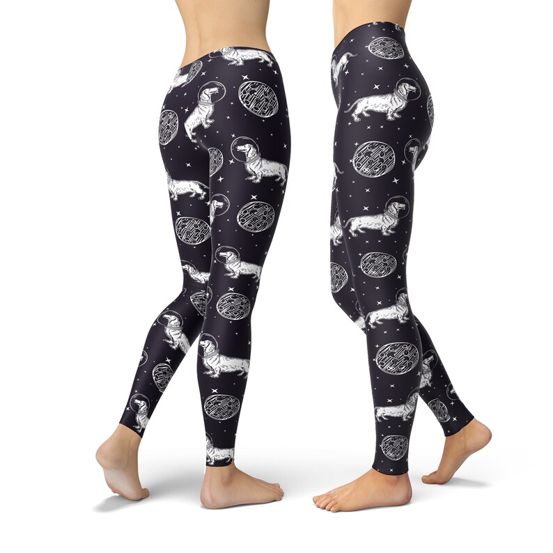 May include: Black leggings with a white print of dachshunds wearing astronaut helmets and floating in space. The print also includes white circles with a textured pattern.