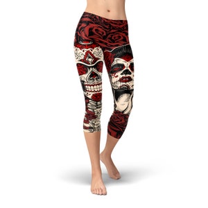 May include: Red, white, and black patterned leggings with a skull and sugar skull design. The leggings are cropped and have a floral pattern.