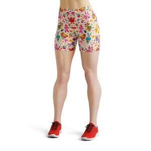 May include: A pair of white athletic shorts with a colourful Easter bunny and egg pattern. The shorts are worn by a person with bare legs and red trainers.