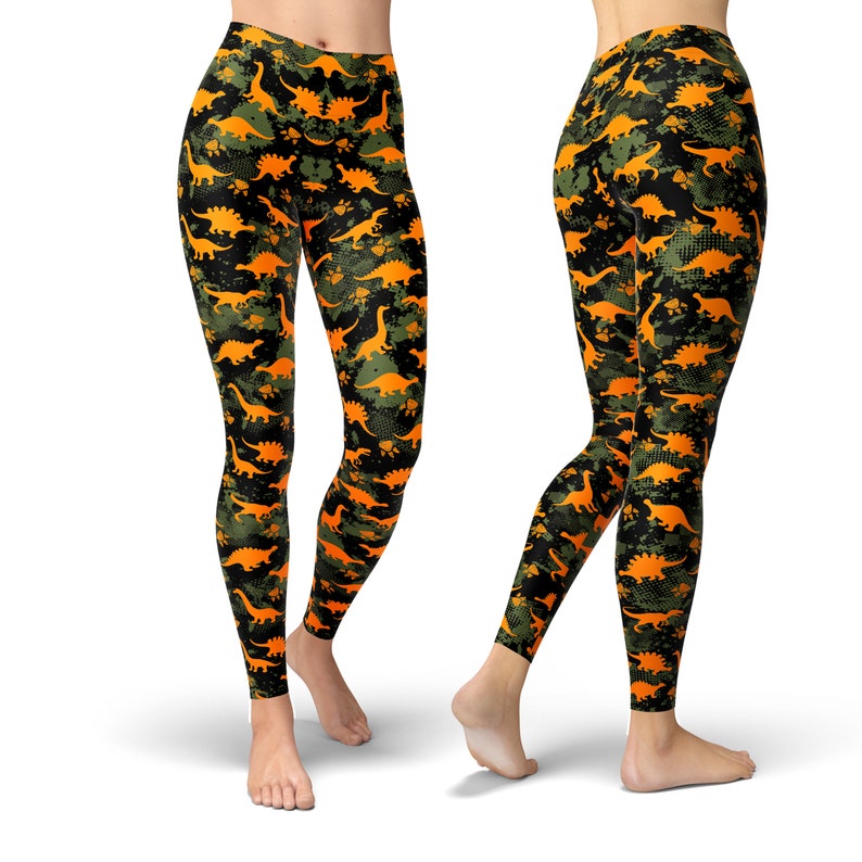 May include: Black leggings with a camouflage pattern featuring orange dinosaur silhouettes.