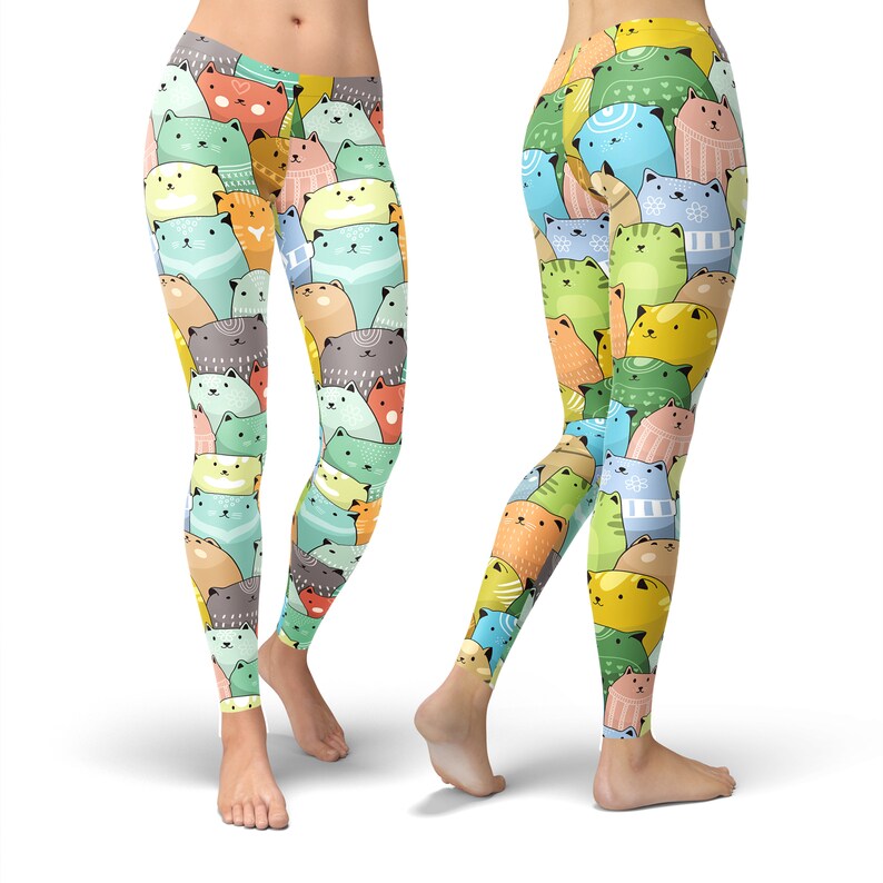 May include: Colorful leggings with a pattern of cartoon cats in various colors and poses. The leggings are a light yellow color with a variety of shades of blue, green, orange, pink, and gray cats.