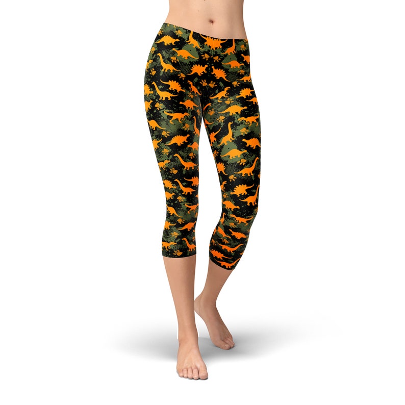 May include: Black and green capri leggings with a pattern of orange dinosaurs.