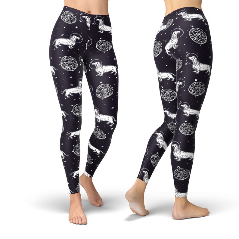 May include: Black leggings with a white print of dachshunds wearing astronaut helmets and floating in space. The print also includes white circles with a textured pattern.
