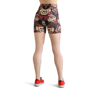 May include: Black athletic shorts with a high waist and a skull and rose print. The shorts have a colorful design with red, yellow, and white accents.