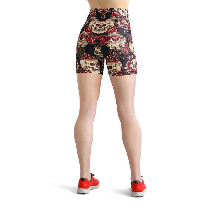 May include: Black athletic shorts with a high waist and a skull and rose print. The shorts have a colorful design with red, yellow, and white accents.