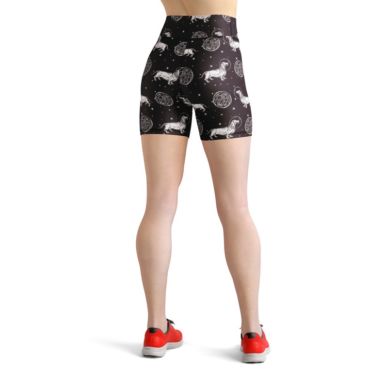 May include: Black athletic shorts with a white print of dachshunds and celestial bodies. The shorts have a high waist and a fitted silhouette.