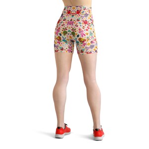May include: A pair of white athletic shorts with a colourful Easter-themed pattern featuring bunnies, eggs, and flowers. The shorts have a high waist and are made of a stretchy, comfortable fabric.