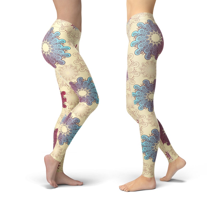 K&ouml;nnte beinhalten: Eine Leggings mit cremefarbenem Hintergrund und einem sich wiederholenden Muster aus blauen und violetten Spiralen. Die Leggings wird an zwei Modellen gezeigt, eines von vorne und eines von der Seite.