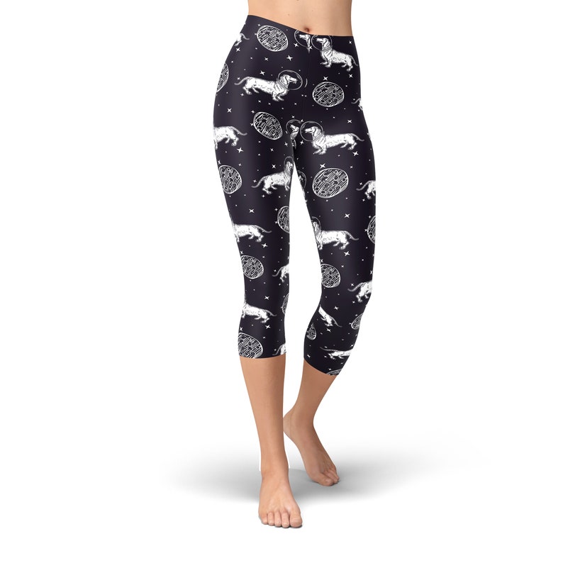 May include: Black capri leggings with a white print of dachshunds wearing astronaut helmets and floating in space.