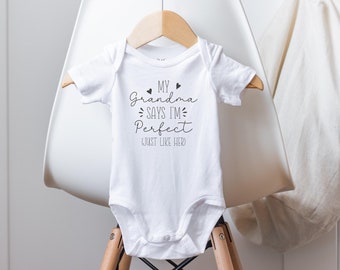 Könnte beinhalten: Weißer Baby-Strampler mit schwarzem Text, der "Meine Oma sagt, ich bin perfekt, genau wie sie" lautet.
