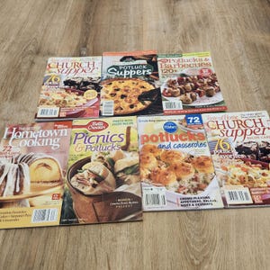 May include: A collection of seven softcover cookbooks featuring titles such as Church Supper, Potluck Suppers, Potlucks & Barbecues, The Best of Hometown Cooking, Picnics & Potlucks, and Potlucks and Casseroles, all displaying food photography.
