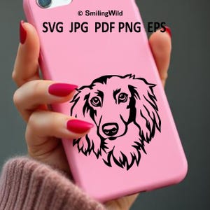 May include: A solid pink smartphone case featuring a black line art illustration of a long-haired dog face. The text "&copy; SmilingWild" and "SVG JPG PDF PNG EPS" is printed in black at the top of the case above the dog graphic.