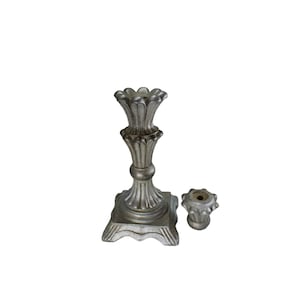 Può includere: Un candelabro d'argento con base quadrata e un design decorativo e ornato. Il candelabro ha due portacandele.