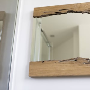 May include: A rectangular mirror with a rustic wooden frame. The frame has a natural wood finish and a unique, irregular shape.