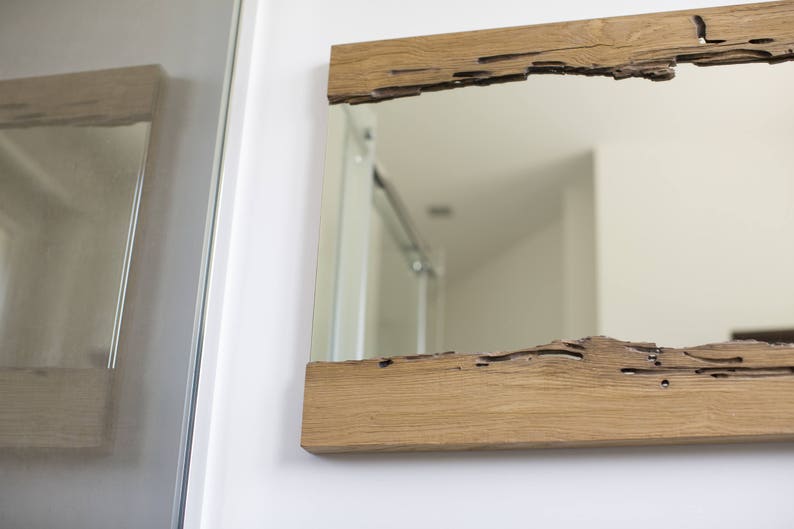 May include: A rectangular mirror with a rustic wooden frame. The frame has a natural wood finish and a unique, irregular shape.