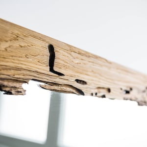 May include: A rustic wooden mirror frame with a natural wood finish and a unique, irregular edge. The frame has a knot hole and other natural imperfections, giving it a handcrafted look.