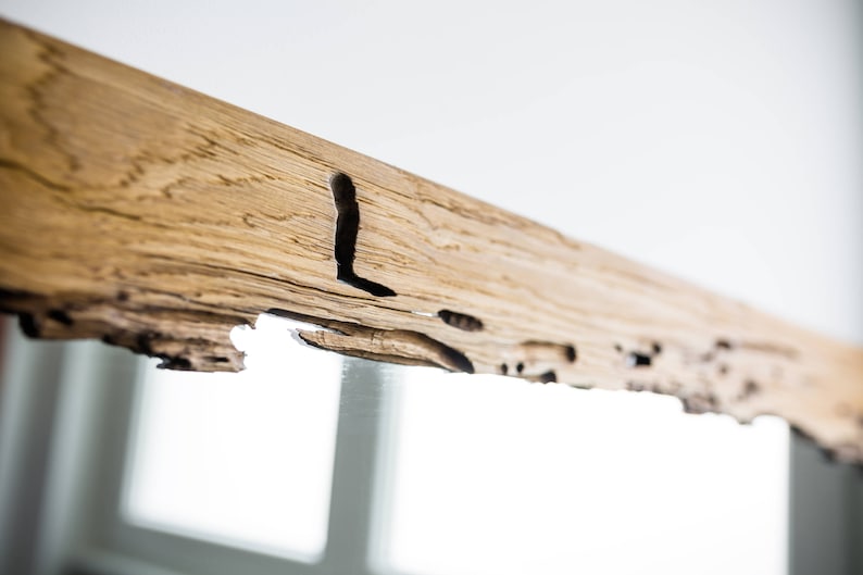 May include: A rustic wooden mirror frame with a natural wood finish and a unique, irregular edge. The frame has a knot hole and other natural imperfections, giving it a handcrafted look.