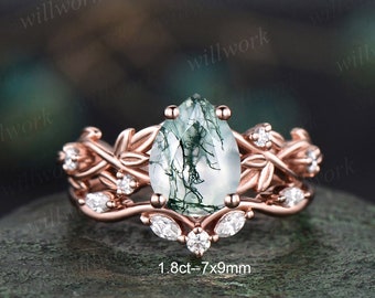 Könnte beinhalten: Verlobungsring aus Roségold mit einem birnenförmigen grünen Moosachat-Edelstein und einem filigranen Blattdesign. Der Ring ist mit kleineren Diamanten besetzt und der Text "1.8ct - 7x9mm" ist unterhalb des Rings sichtbar.