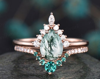 Könnte beinhalten: Ein Verlobungsring mit einem birnenförmigen grünen Moosachat in Roségold, umgeben von einem Halo aus kleineren Diamanten und einem passenden Band mit smaragdgrünen Edelsteinen.