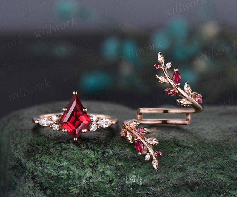 May include: Two rose gold rings with red gemstones. One ring features a square-shaped red gemstone surrounded by smaller white gemstones. The other ring is a delicate band with a leaf design and red gemstones.