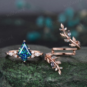 May include: A set of three rose gold rings with a green and blue gemstone in a triangular setting. The rings are adorned with small diamonds and a delicate leaf design.