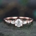 May include: A rose gold engagement ring featuring a round centre stone and pear-shaped accent stones.