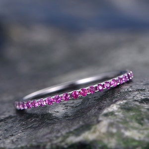 May include: A delicate silver band ring with a row of small pink gemstones.