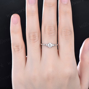 May include: A delicate silver engagement ring with a round centre stone and smaller accent stones on the band.