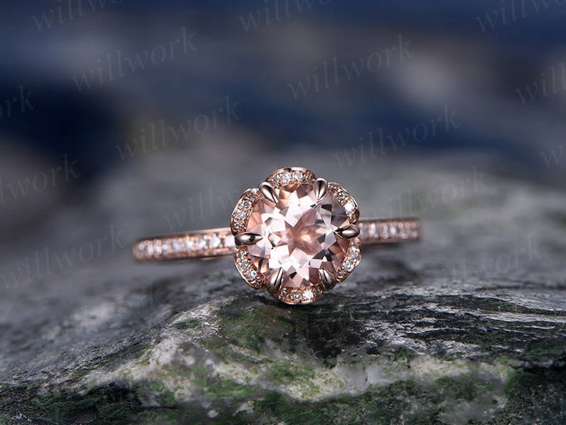 May include: A rose gold engagement ring with a round morganite center stone and a halo of smaller diamonds. The band is also set with smaller diamonds.