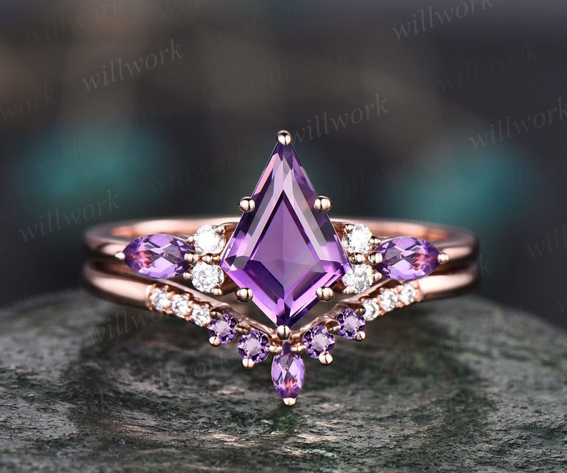 May include: A rose gold engagement ring with a large, purple, square-shaped amethyst gemstone. The ring has a delicate band with smaller amethyst gemstones and diamonds.