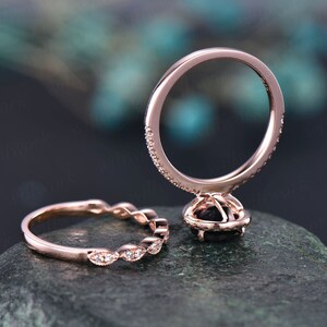 May include: Rose gold engagement ring set with a black centre stone and a halo of smaller stones. The band is encrusted with small accent stones. The matching band features a series of marquise-shaped stones.