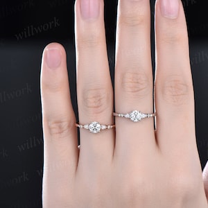 May include: Two delicate rings with small diamonds set in a rose gold band. The rings are on a person's finger.
