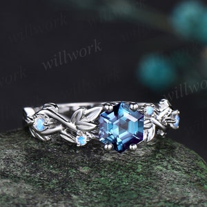 May include: A silver ring with a blue gemstone surrounded by smaller white gemstones and a leafy design.