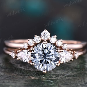 May include: A rose gold engagement ring set with a large round center stone and smaller pear-shaped and round accent stones.