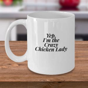 May include: White ceramic coffee mug with a black inscription that reads "Yep, I'm the Crazy Chicken Lady".
