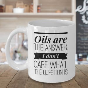 May include: White ceramic coffee mug with a black graphic that reads "Oils are the answer. I don't care what the question is."