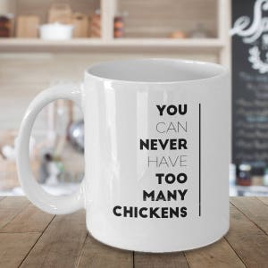 May include: White ceramic coffee mug with a black graphic that reads "You can never have too many chickens".
