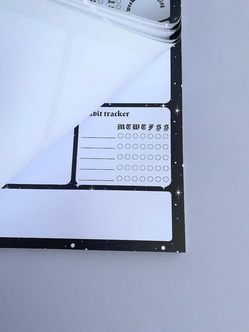 May include: A black and white habit tracker with a starry background. The tracker has a section for each day of the week, labeled "M T W T F S S".