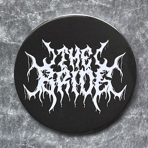 May include: Black and white button with the text "THE ABYSS" in a stylized, gothic font.