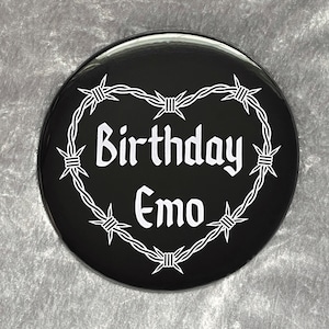 Può includere: Bottone nero e bianco con un design a forma di cuore di filo spinato. Il testo "Birthday Emo" è all'interno del cuore.