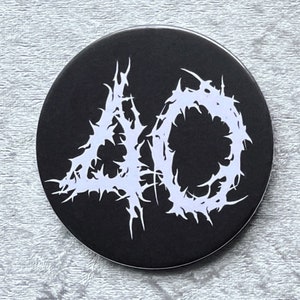 May include: A black and white button with the number 40 in a stylized, spiky font.