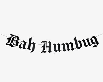 May include: Black banner with the words "Bah Humbug" in a gothic font. The banner is strung on a thin white string against a white background. The letters are bold and easy to read.