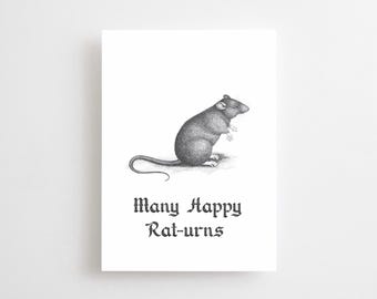 May include: A black and white illustration of a rat on a white background. The rat is in a seated position, with its tail curled. The text "Many Happy Rat-urns" is below the rat in a gothic font. The image is on a rectangular card.
